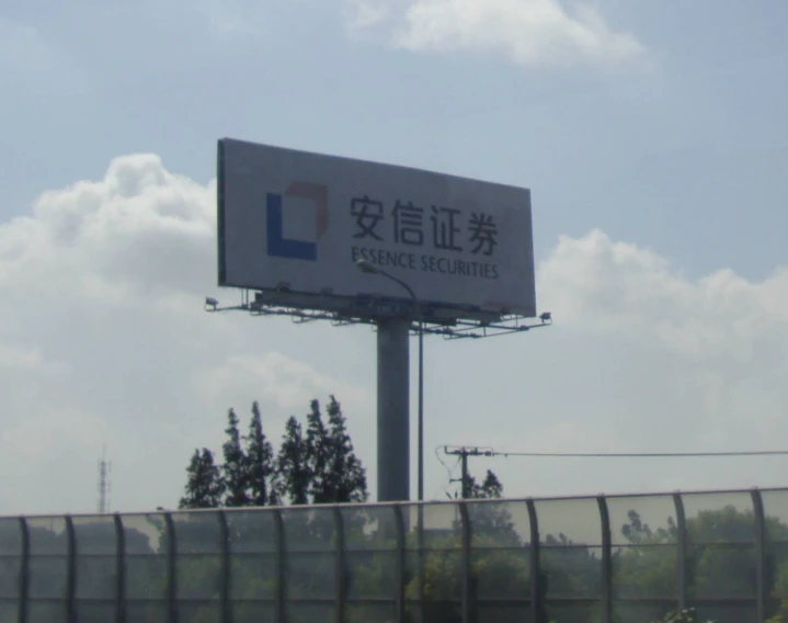 a large billboard above a fence with trees in the background