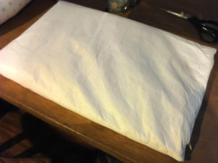 the sheet is being unfolded onto a wooden table