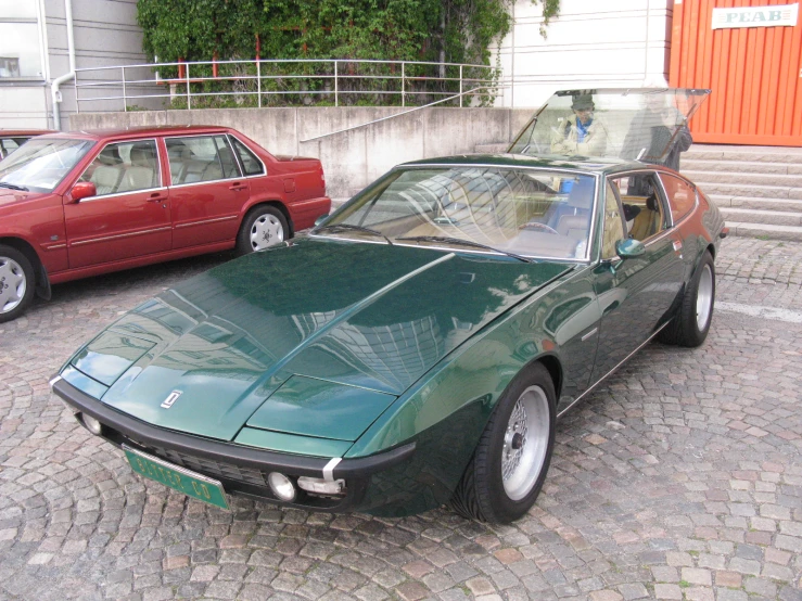 a green and black car parked on the sidewalk