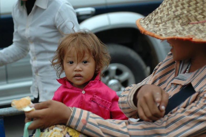 young child wearing pink shirt sitting in chair by truck