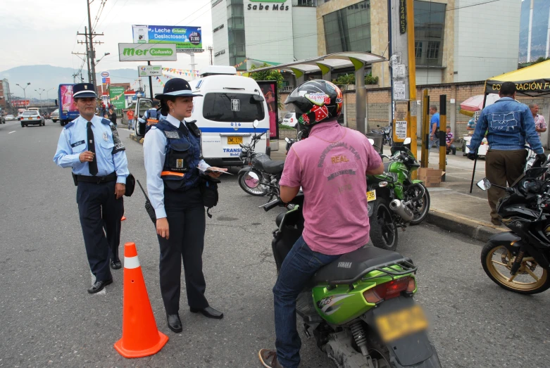 two officers are standing near motorcycles that are parked in the street