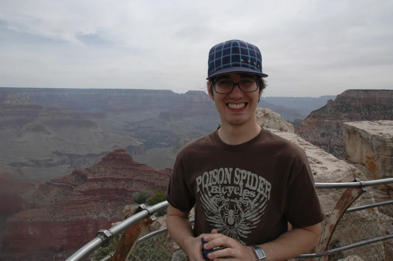 a man with glasses and a hat on poses for a picture