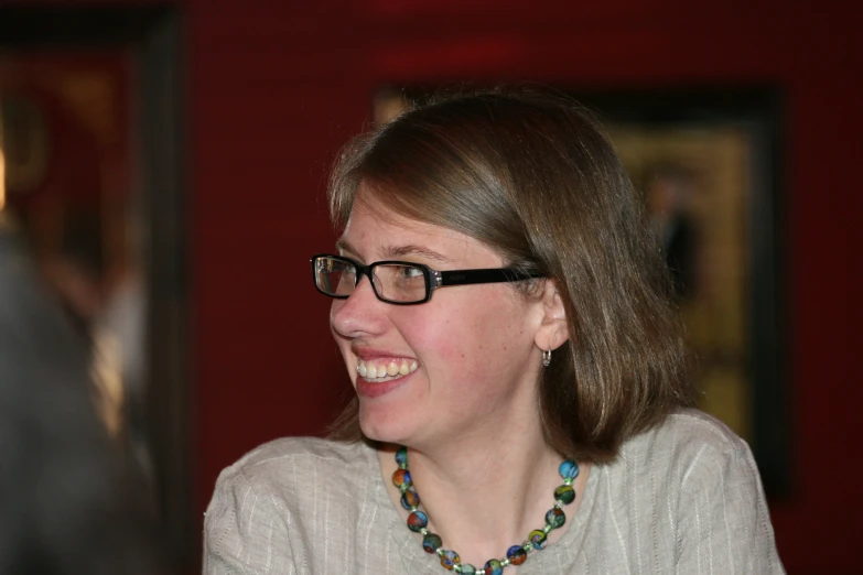 a young lady wearing eye glasses talking to someone