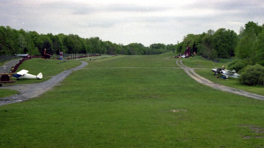 a grassy area with many different planes parked in the grass