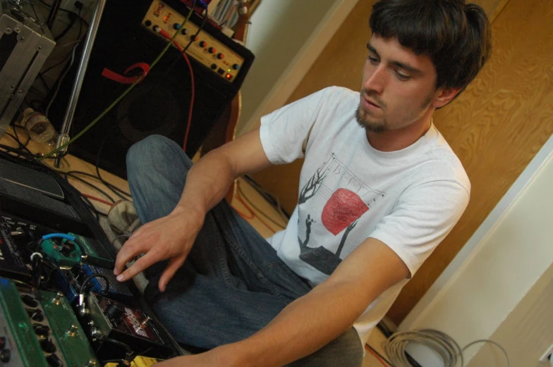 man sitting in front of sound equipment working on electronics