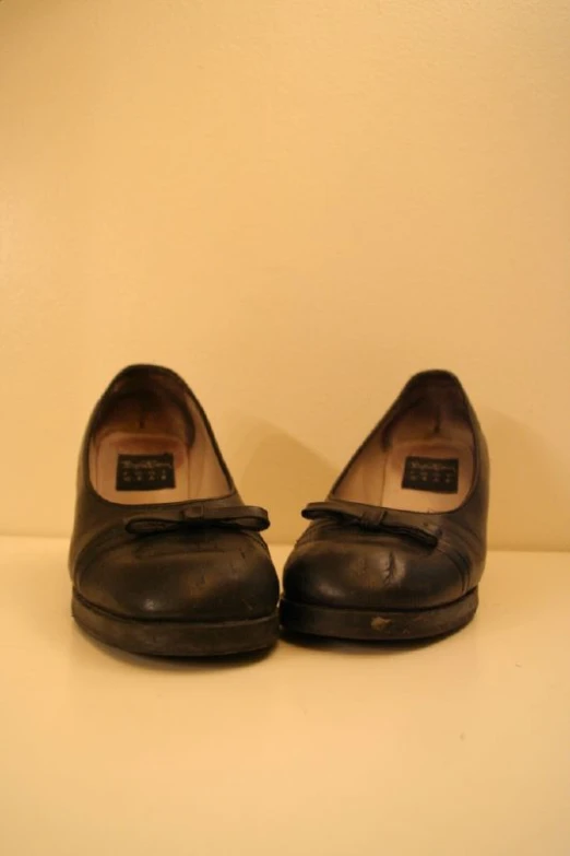 pair of black flats sitting in front of a wall