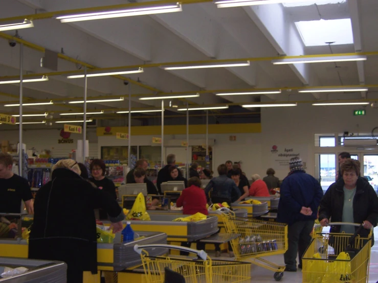 people are shopping in an empty store with yellow carts