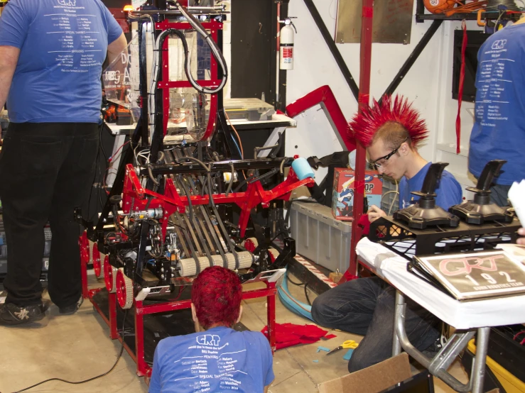 two men are working on an intricate red machine