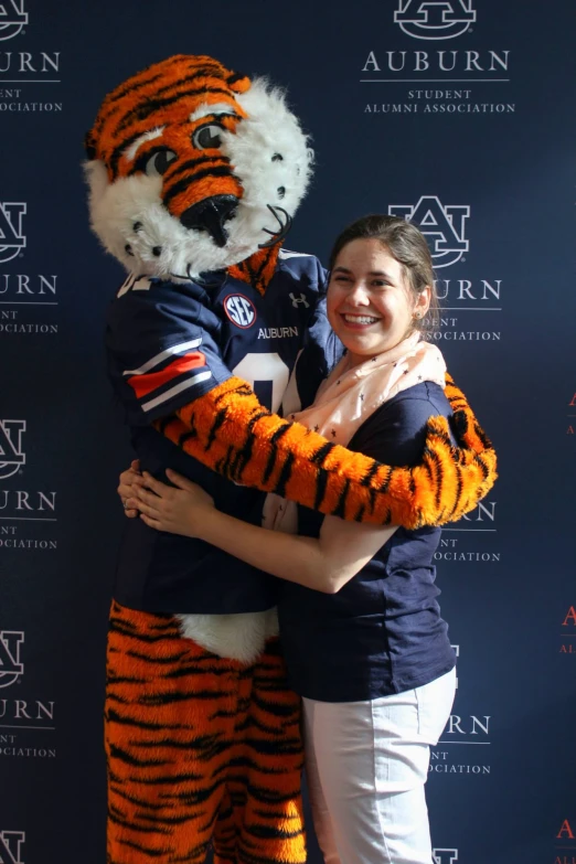 the two young women are hugging a mascot