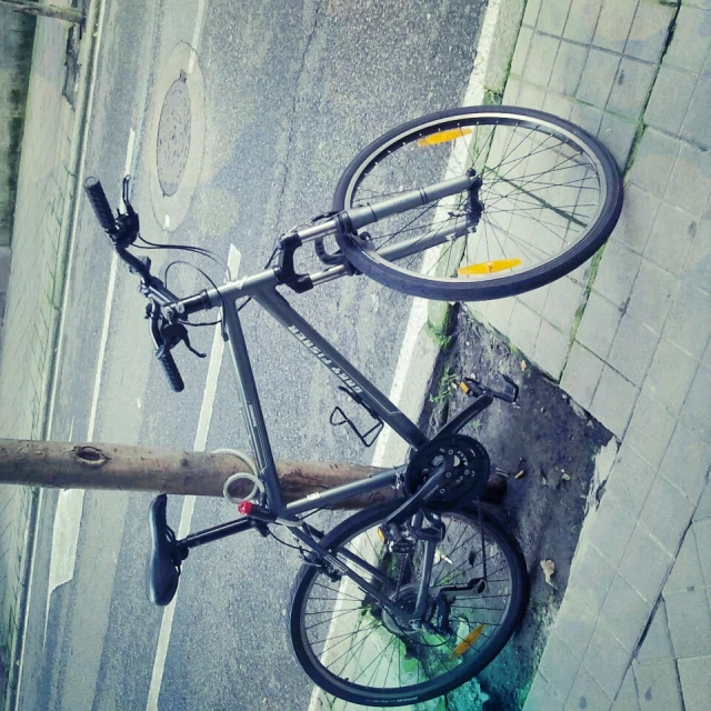 a bicycle is locked to a pole on a street