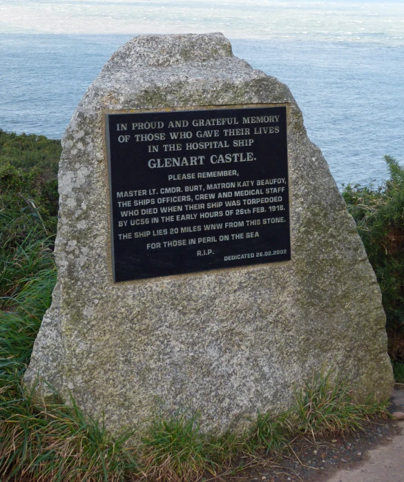 a memorial stone sitting next to the ocean