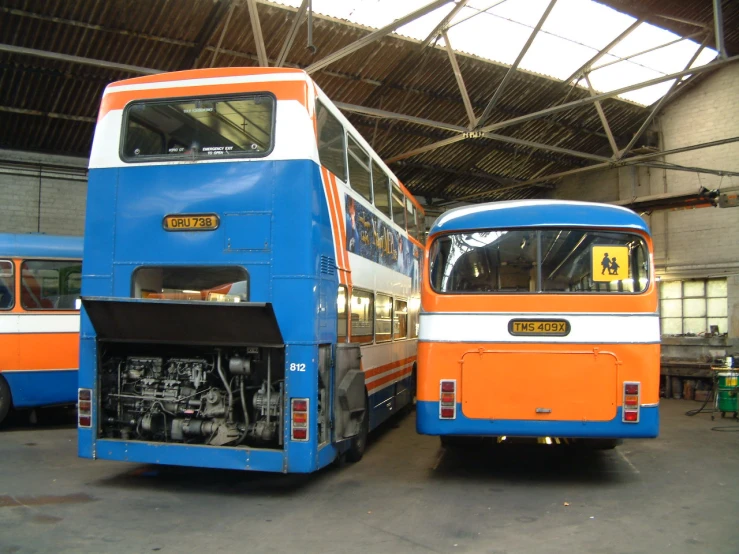 two identical busses are shown in an outdoor garage