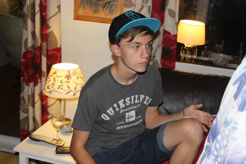 a boy with his hat on, sitting on a couch