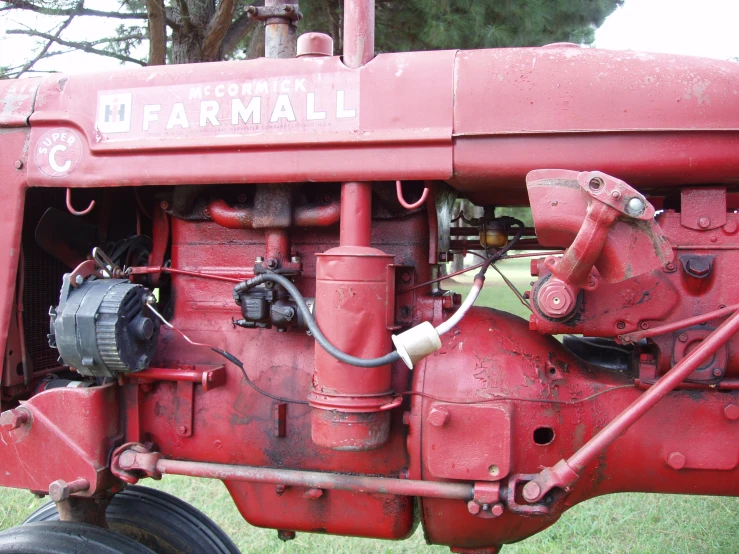 an old farmall tractor with a big hose