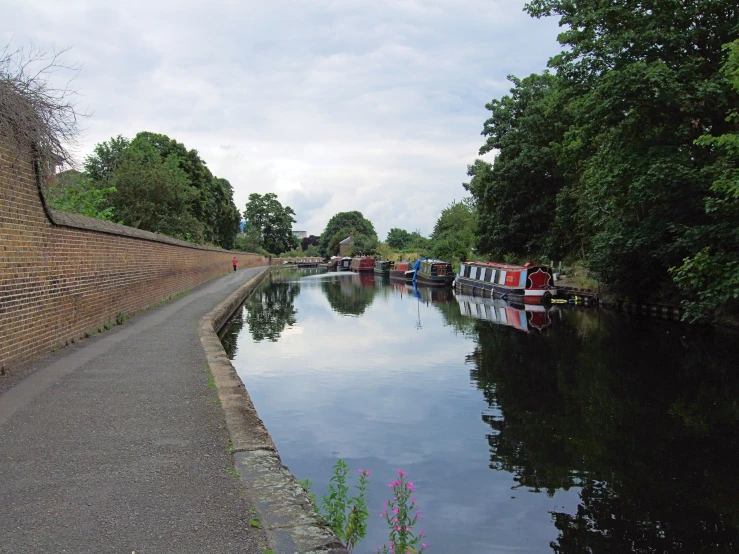 a long line of boats docked on the side of a river