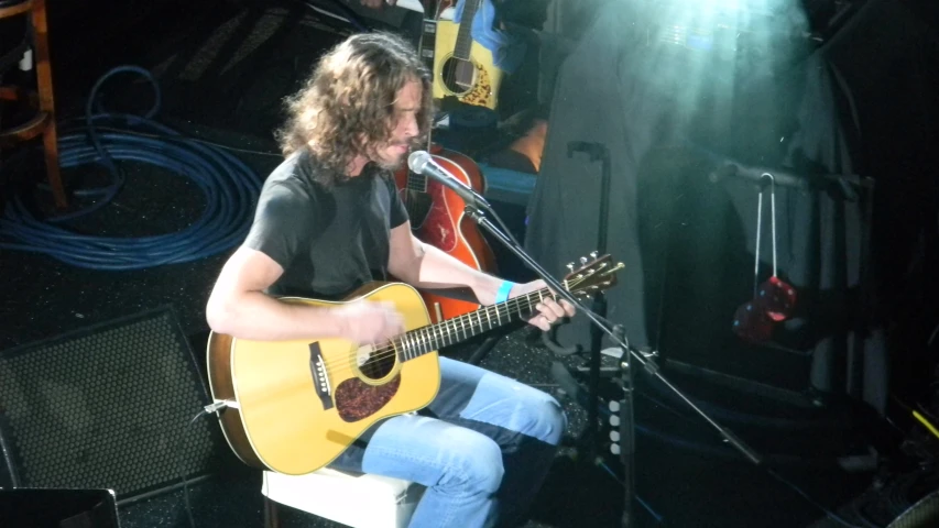 a man playing guitar while sitting down