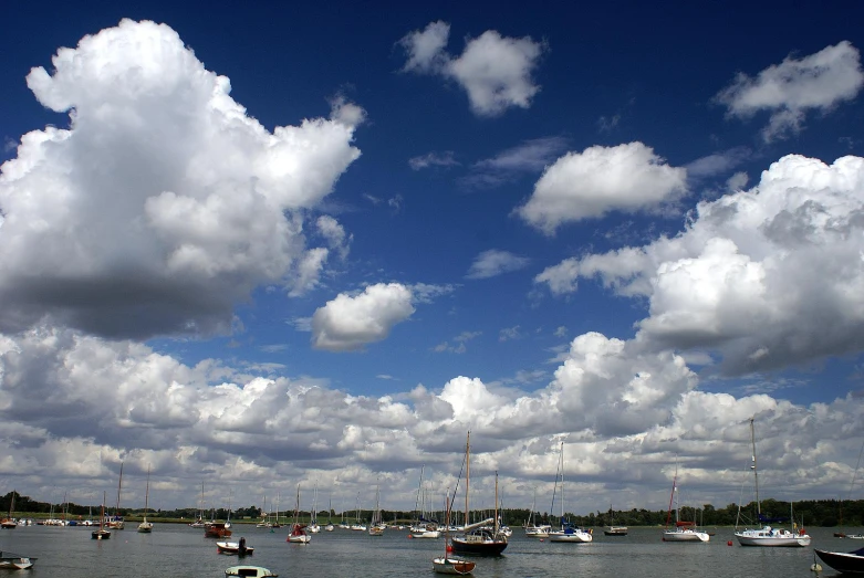 several boats in a body of water under a cloudy blue sky