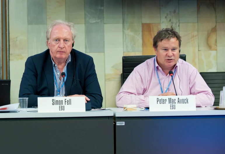 the two men sit next to each other during a panel