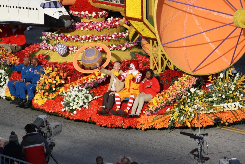 a float features men seated at each side with flowers