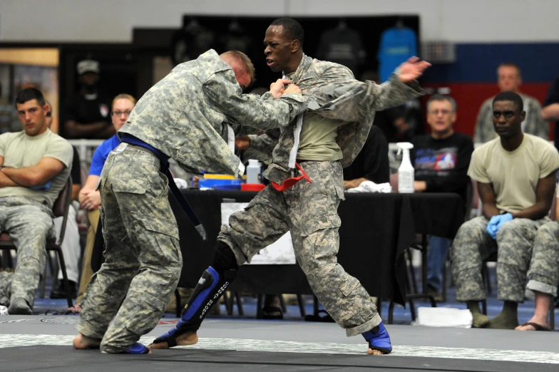 two people in camouflage uniforms fighting on the ground