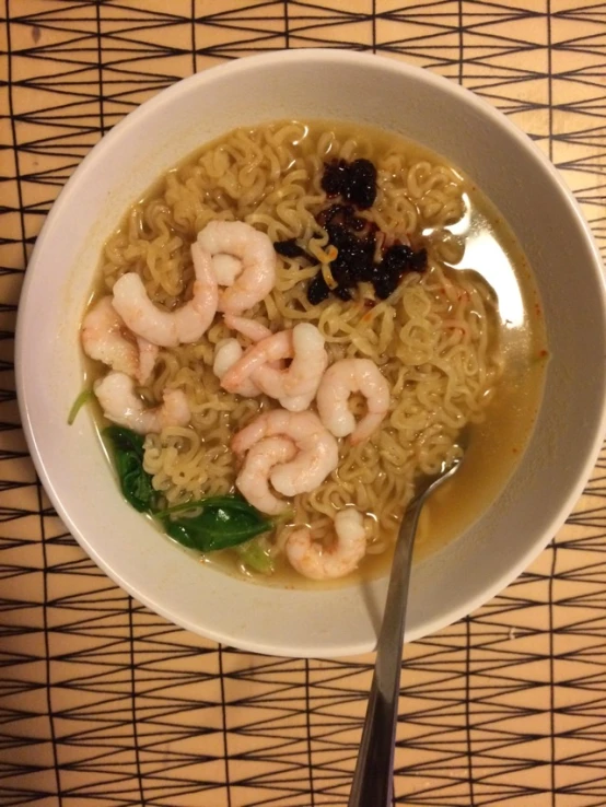 shrimp and noodle soup on bamboo mat with spoon