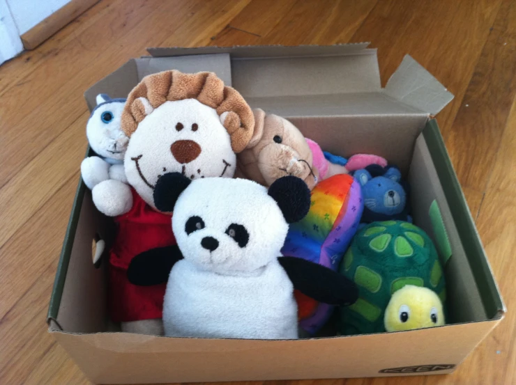 a box filled with stuffed animals on top of a wooden floor