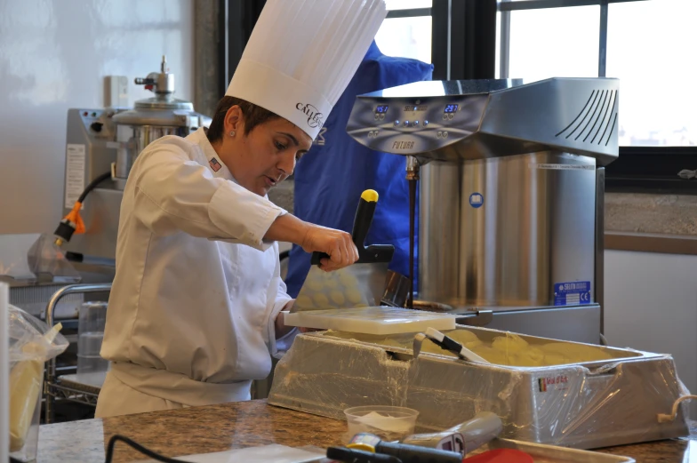 a person cooking in a kitchen while wearing a chef's hat