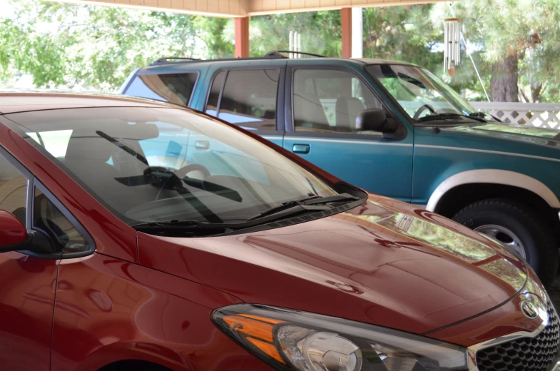 the back end of two red cars with hood vents