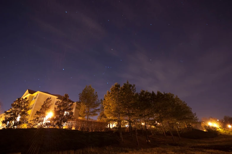 a house sitting between trees at night in the woods