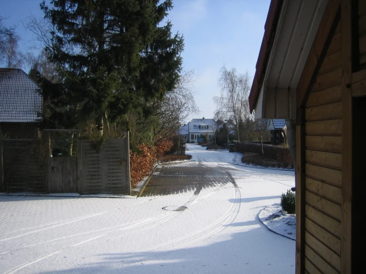 view down a snow covered driveway towards homes