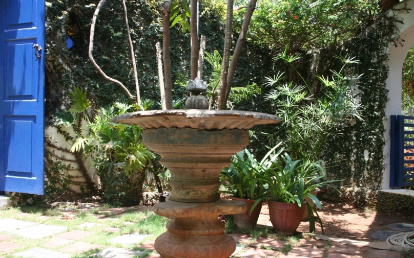 an outside fountain in a garden next to green plants