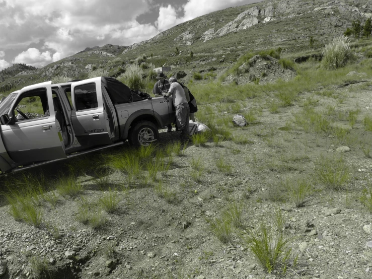 a silver truck parked on a dirt road in the mountains