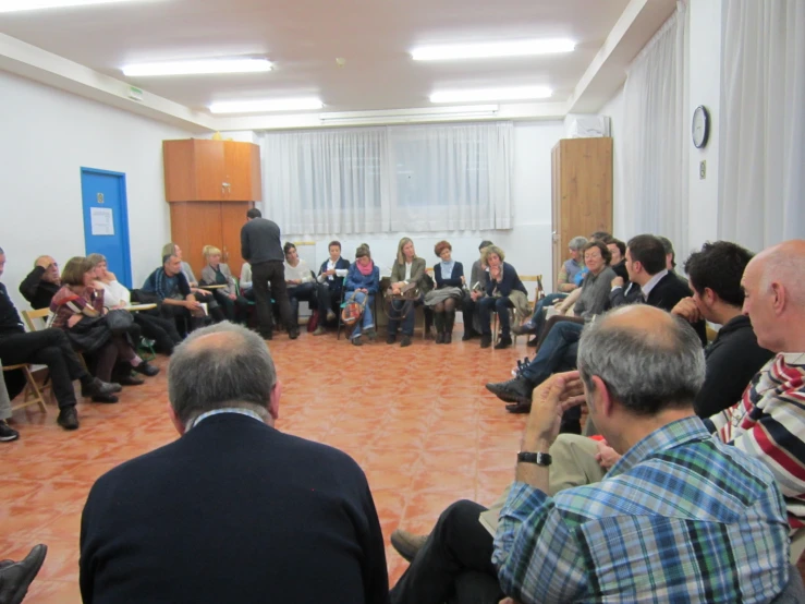 a room full of people watching several people speaking