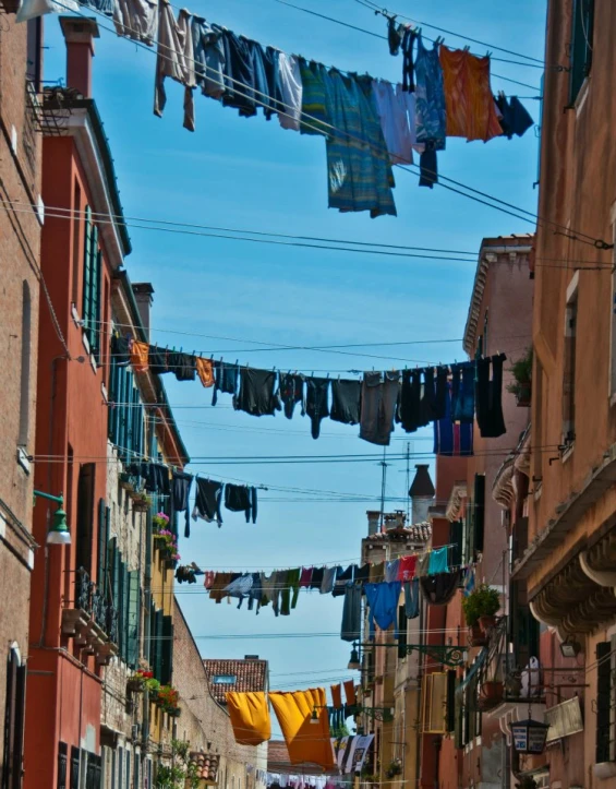 a cobblestone alley in italy is lined with buildings and laundry