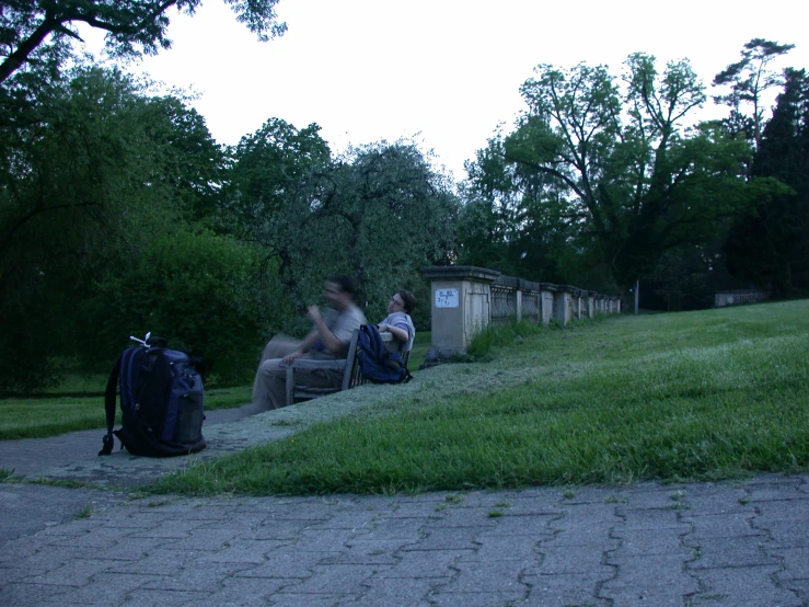 a couple of people sitting down outside talking and another person walking by them