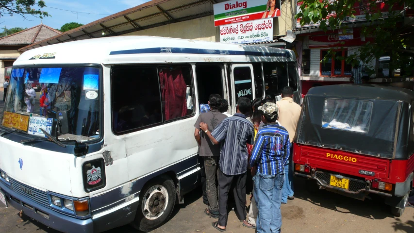 some people standing outside a big white bus