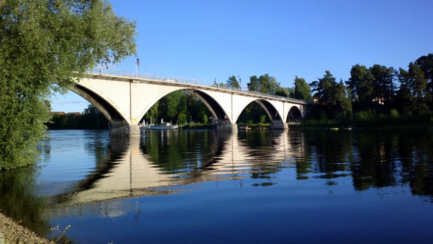 a white bridge is over water with trees in the background