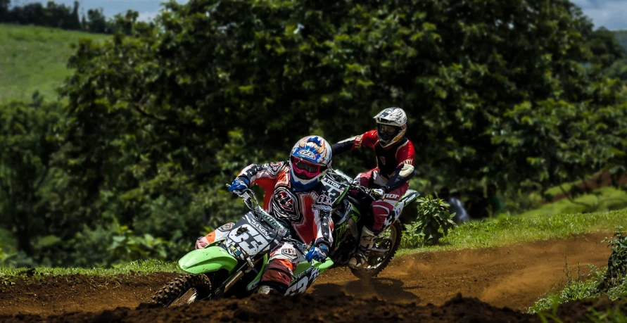 two people riding dirt bikes on a dirt road