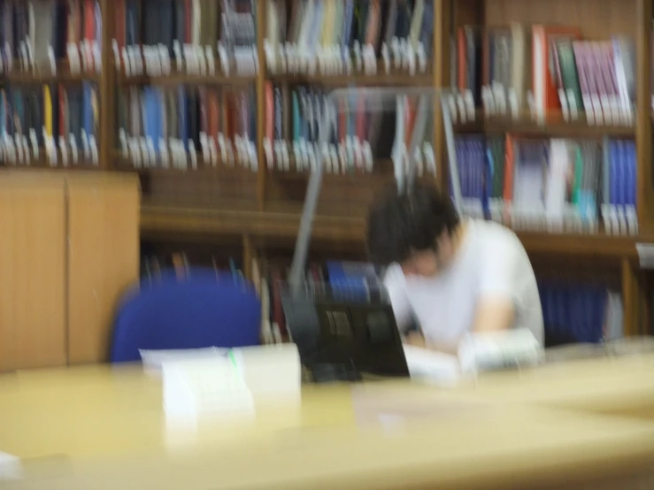 blurry pograph of man looking at book at liry
