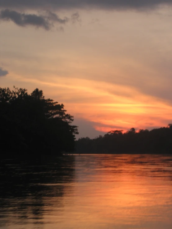 a sunset over the river with some trees