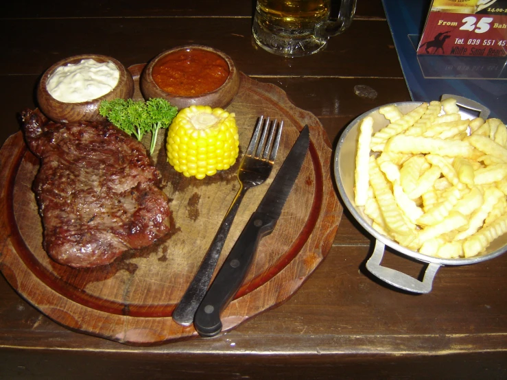 a table with plates of food that include fries, steak and cole slaw