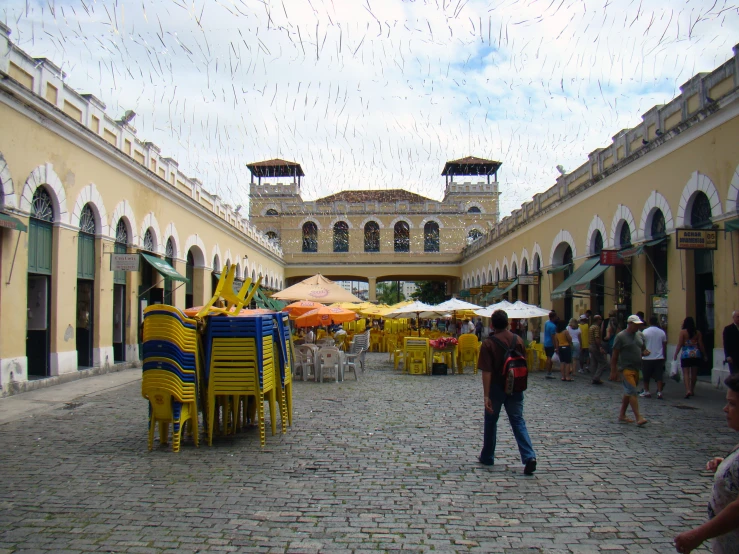 people walking through an indoor courtyard area with tables and umbrellas