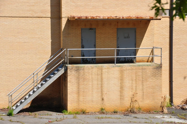 a set of stairs lead up to a building next to a brick wall