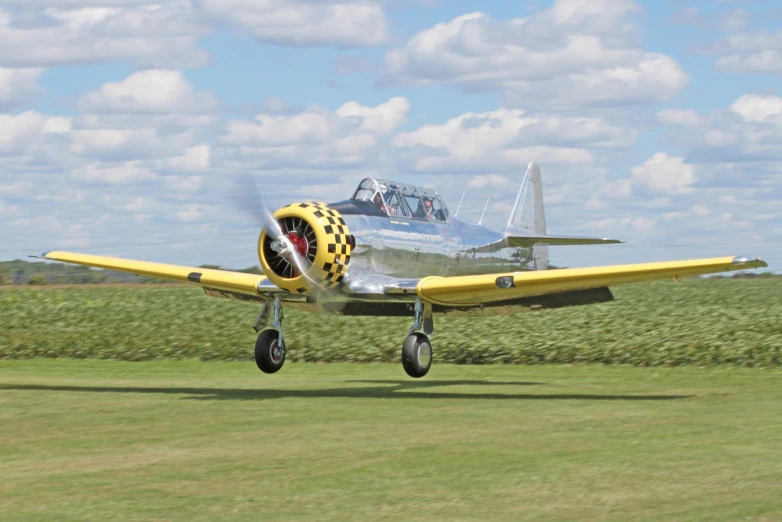 a yellow biplane is flying on the runway