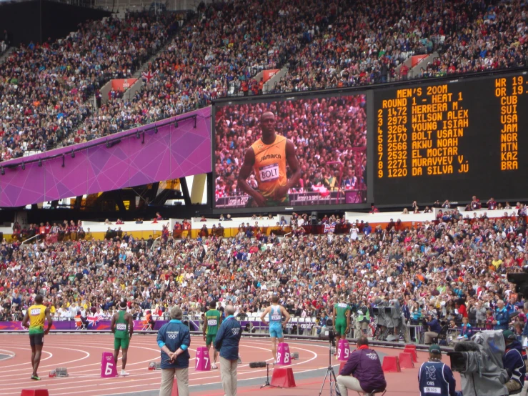 a crowd watching a men's race on the scoreboard