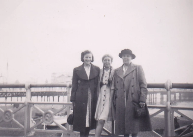 black and white po of three woman in front of a bridge