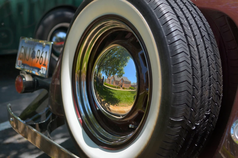 a large car tire reflected in another vehicle's front tire