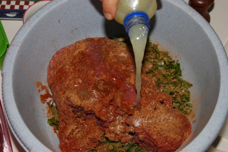 a person pouring dressing on food into a bowl