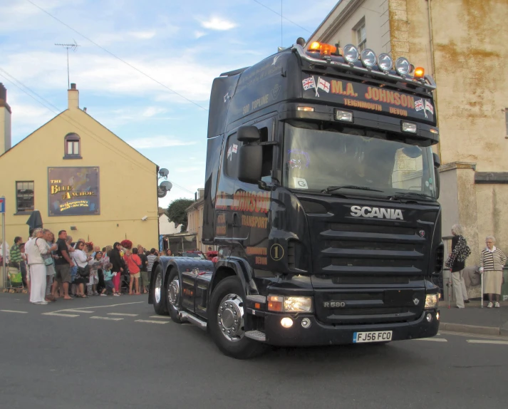 a large truck is parked in front of a group of people