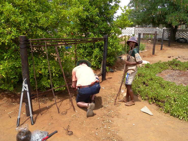 two people are working in a garden near bushes